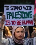 Woman Holding Sign That Reads 'To Stand With Palestine is to be Human'